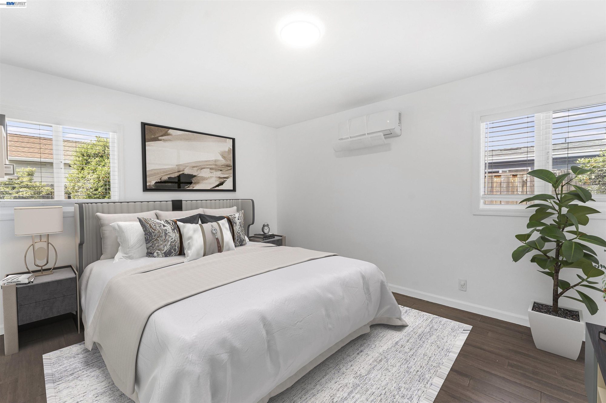 Primary bedroom staged with queen bed and mini-split